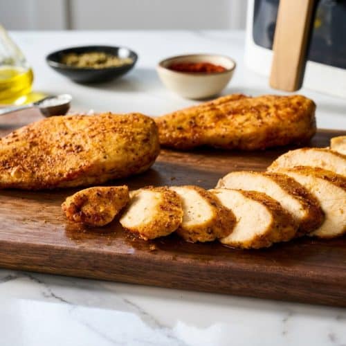 Golden brown air fryer chicken breast with a crispy cornstarch micro-crust resting on a cutting board.