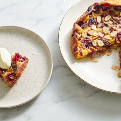 Cherry clafoutis with golden brown butter custard and a toasted almond crust in a rustic ceramic baking dish.