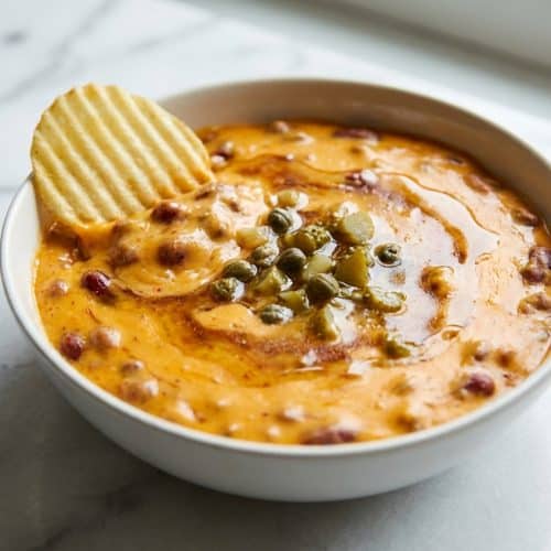 Creamy chili cheese dip in a skillet, featuring a savory brown butter and pickled brine bloom for complex depth.