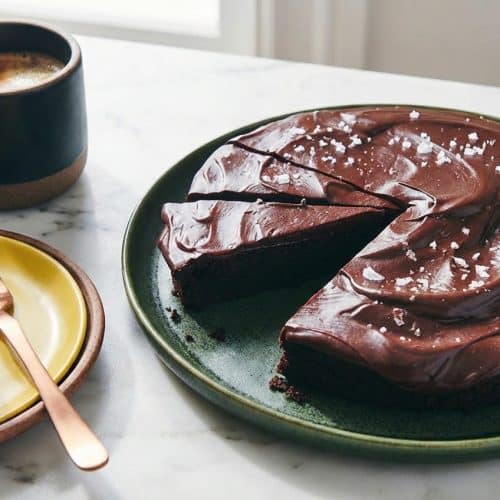 A fudgy brown butter flourless chocolate cake topped with glossy chocolate ganache and sparkling flaky sea salt.
