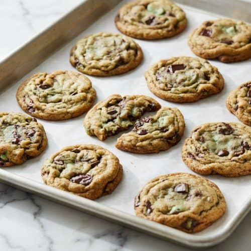 Mint chocolate chip cookies with nutty brown butter and puddles of dark chocolate chunks on a wire cooling rack.