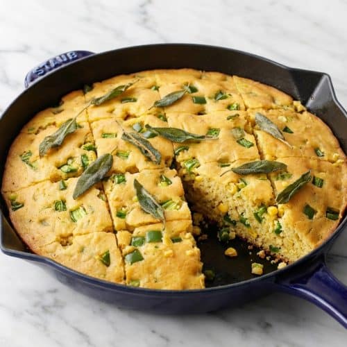 Slices of jalapeño cornbread in a cast-iron skillet infused with savory brown butter and fresh sage.