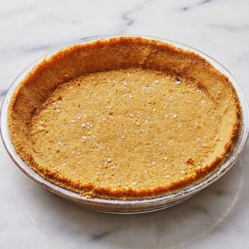 Golden brown butter graham cracker crust with a sprinkle of sea salt in a glass pie plate.