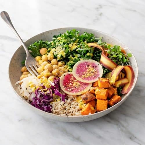 Vibrant Buddha bowl topped with savory miso-nutritional yeast dusting and fresh plant-based protein.