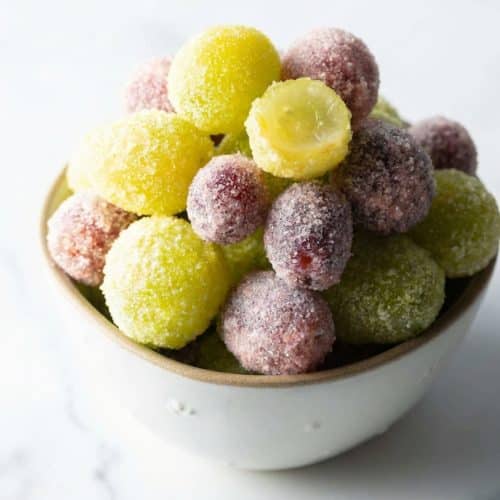 Frozen candied grapes recipe featuring green seedless grapes coated in Jell-O powder and citric acid for a sour patch twist.