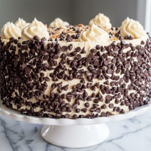 Layered cannoli cake with stabilized mascarpone-ricotta filling and mini chocolate chips on a ceramic cake stand