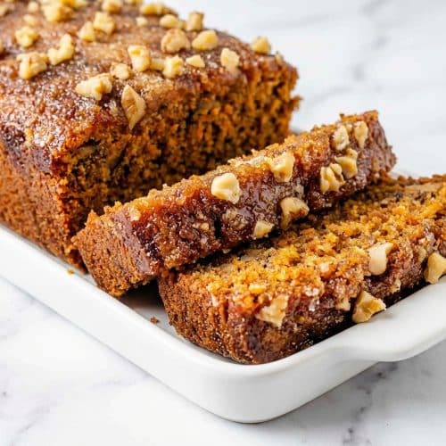 Slices of carrot cake loaf featuring a crackly brown butter sugar crust and thick cream cheese frosting.