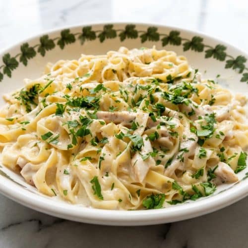 Creamy chicken fettuccine alfredo with a nutmeg infusion and glossy pasta water emulsion in a skillet.