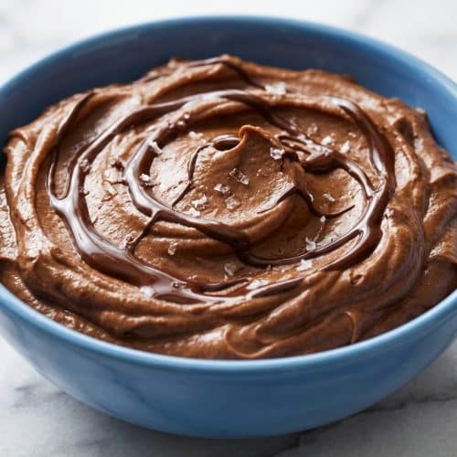 Creamy Chocolate Avocado Pudding topped with a swirl of melted 70% dark chocolate and flaky sea salt.