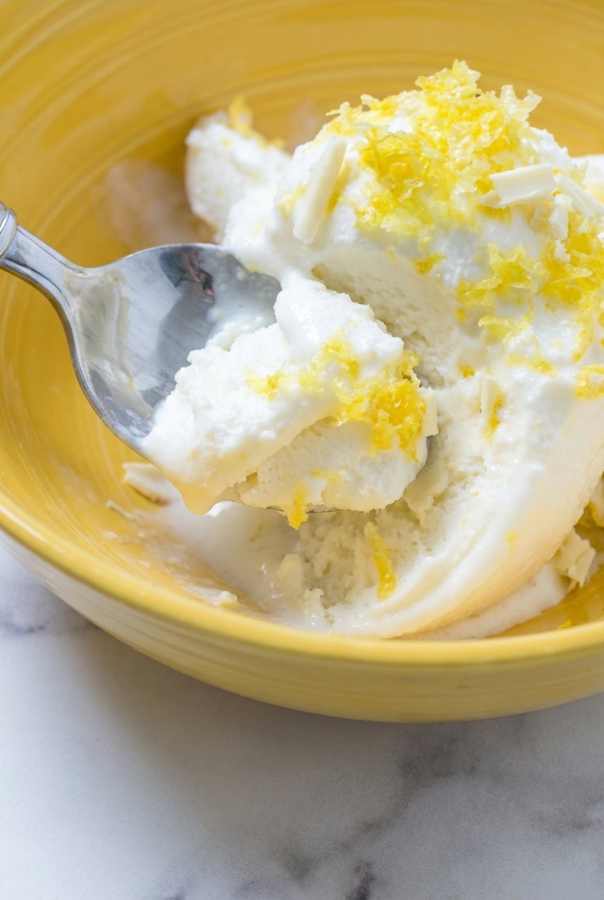 Close-up of churning lemon ice cream in a freezer bowl showing a smooth and thick emulsification.