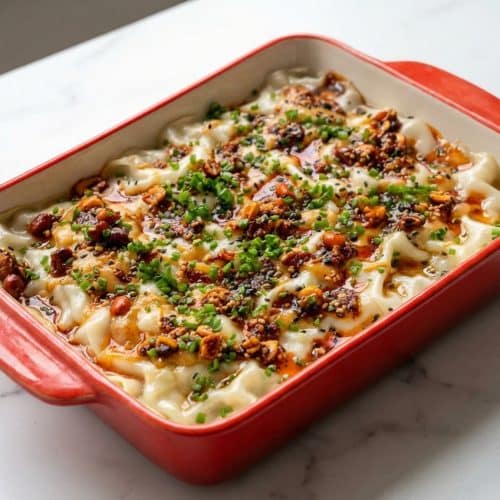 Layers of dumpling lasagna featuring a golden, crispy bottom finish and savory pork filling in a baking dish.