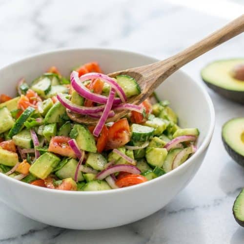 Bowl of fresh Cucumber Tomato Avocado Salad with cilantro and red onions macerated in lemon juice for a milder flavor.