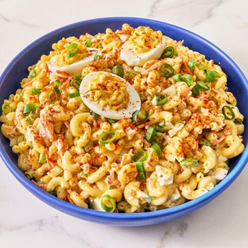 Creamy deviled egg pasta salad featuring a savory umami-brine emulsion and a dusting of smoked paprika.