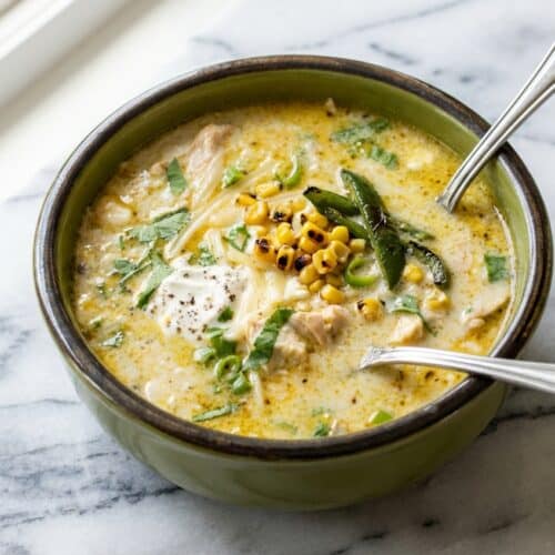 Creamy green chicken enchilada soup in a bowl, showing depth of flavor from the double-char technique.