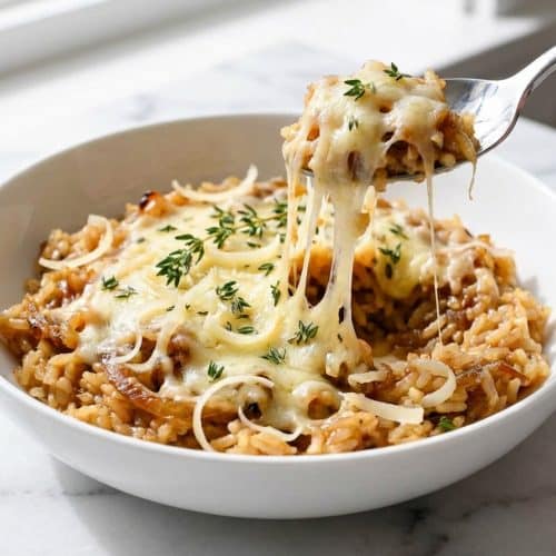 A casserole dish of French onion soup rice with a bubbly, golden-brown melted Gruyère cheese top, creating a perfect bistro finish.