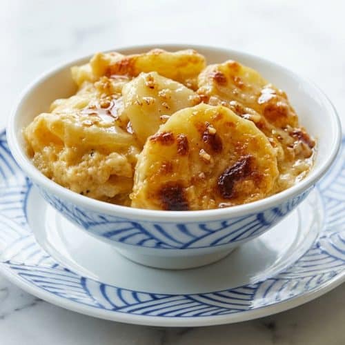 Golden bubbly potatoes au gratin in a casserole dish made with a savory garlic-infused brown butter roux.