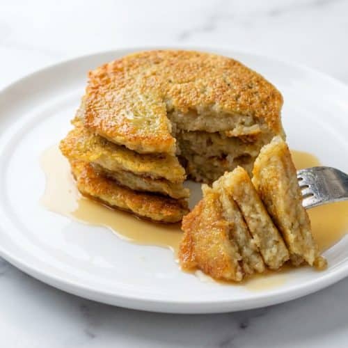 Golden brown german potato pancakes topped with applesauce, featuring an ultra-crispy dual-texture crust and tender center.