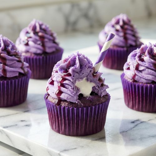 Vibrant Grape Soda Cupcakes frosted with buttercream and featuring a hidden marshmallow fluff core inside.