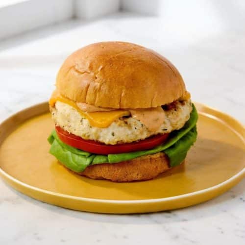 Juicy grilled chicken burgers on a toasted bun, made tender with mayo mixed into the patty before flash-freezing.