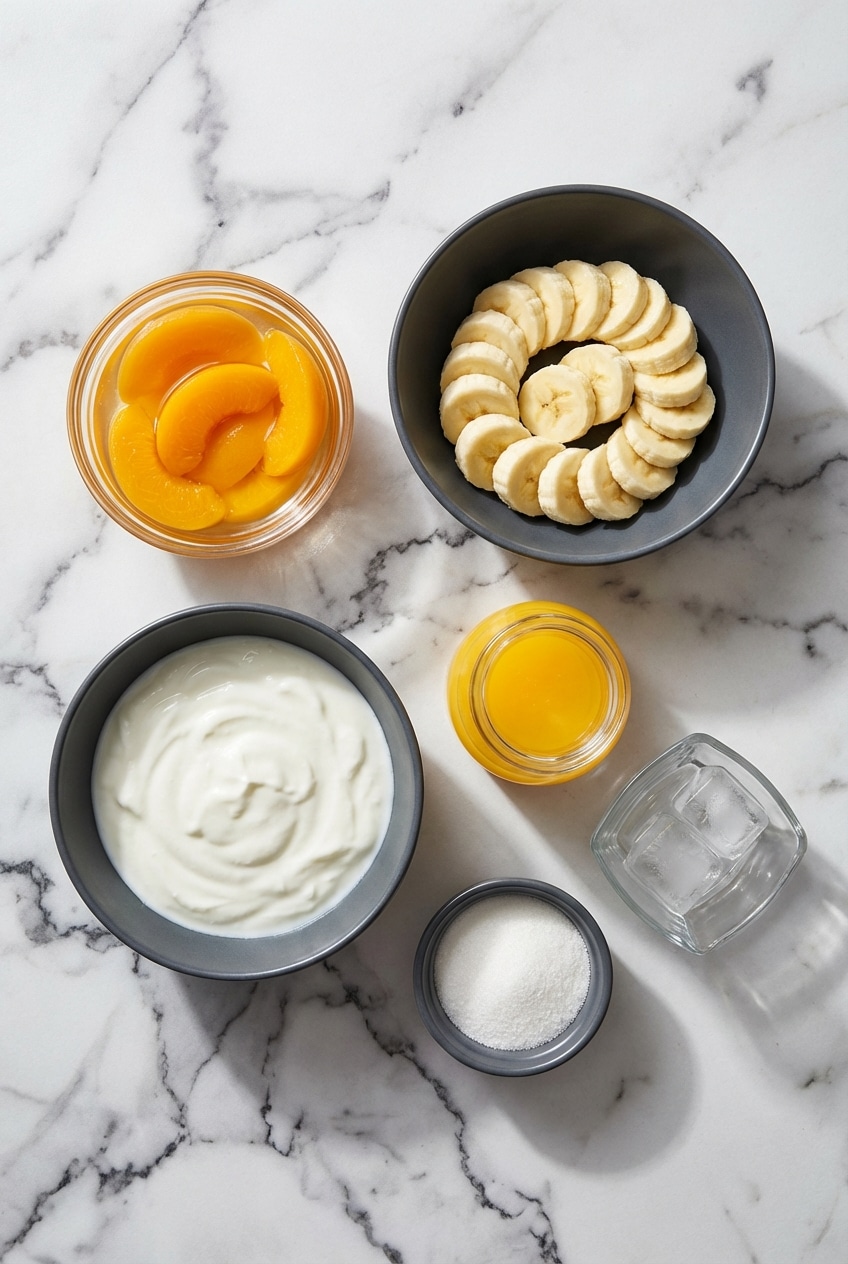 Flat lay of frozen fruit, Greek yogurt, and natural sweeteners used for a banana peach smoothie.