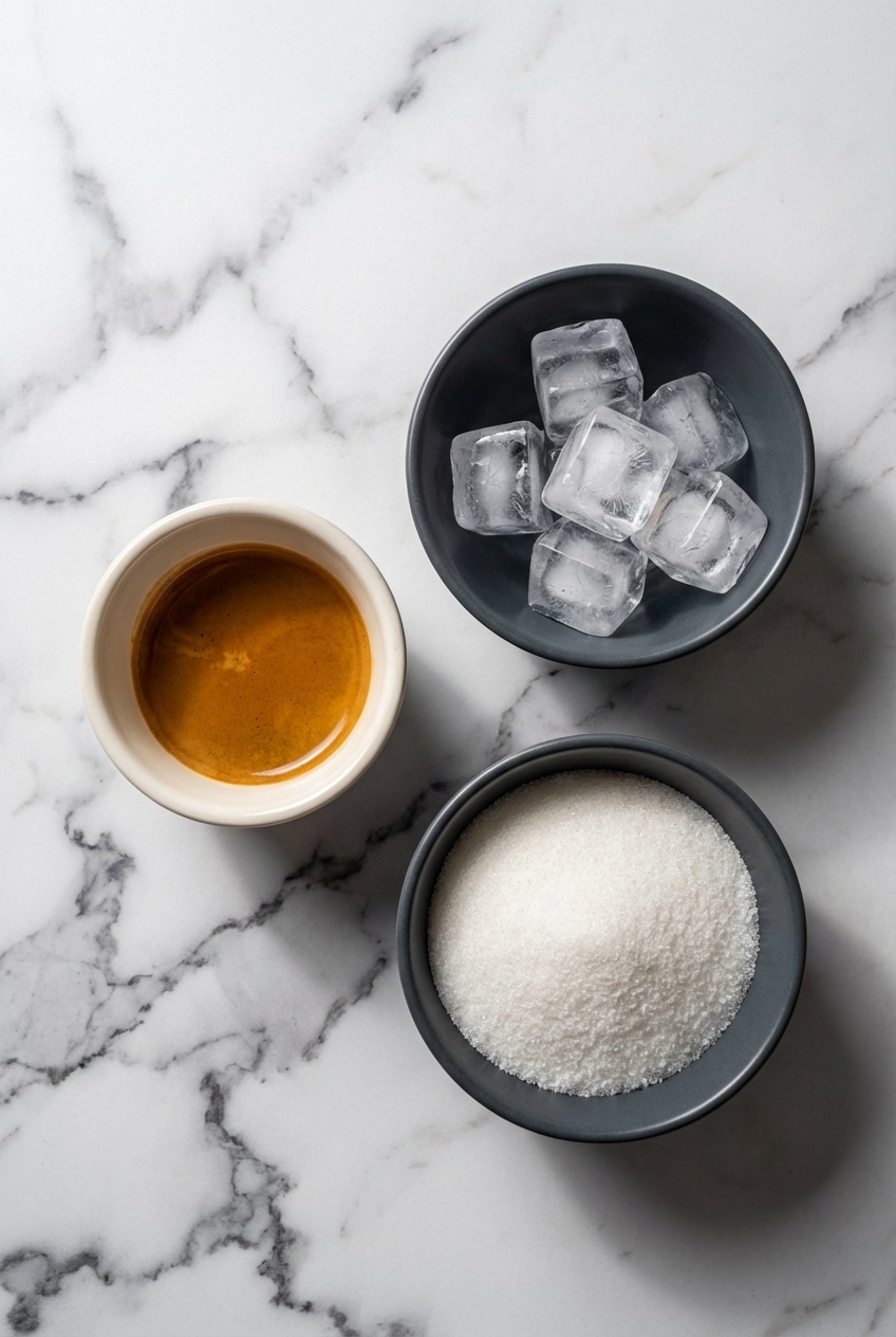 Flat lay of ingredients for Freddo Espresso recipe including Arabica beans, a double shot espresso, and ice cubes.