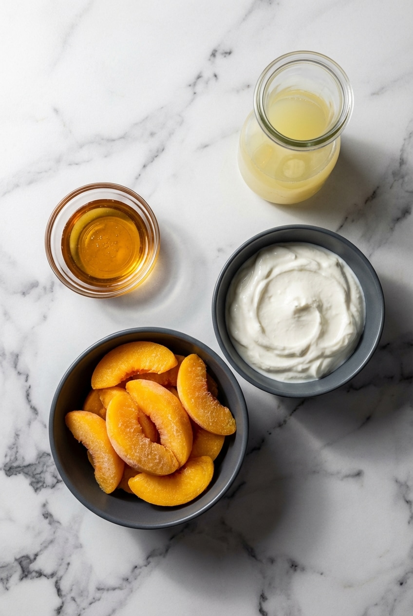 Flat lay of freestone peaches, Greek yogurt, honey, and bourbon for making homemade peach frozen yogurt.