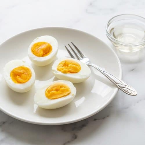 Peeling smooth instant pot hard boiled eggs made with a splash of vinegar for effortless shell removal.