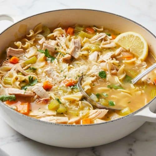 Steaming bowl of leftover turkey soup with egg noodles, enriched with gravy and a Parmesan broth for a deep umami twist.