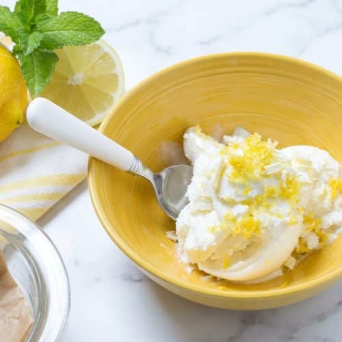 Creamy lemon ice cream scoops topped with macerated lemon-sugar zest and delicate white chocolate flecks.