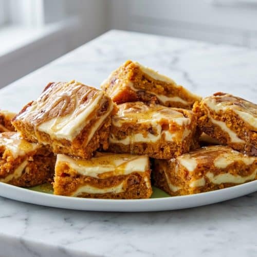 Moist carrot cake bars with a miso brown butter glaze and cream cheese swirl, topped with toasted pecans.