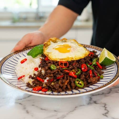 Pad kra pao recipe showing ground meat coated in an emulsified broth glaze, topped with a crispy rendered fat egg fry.