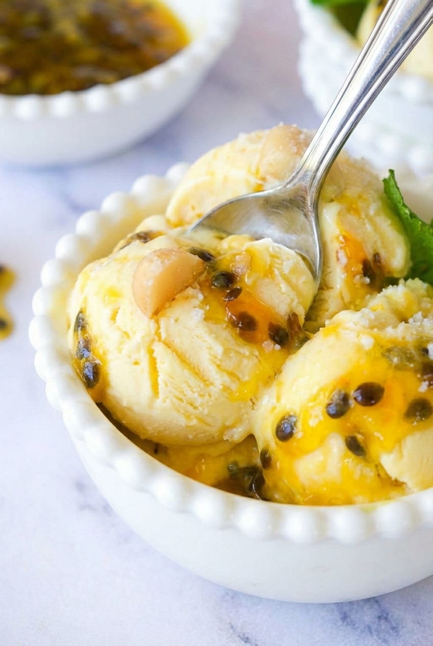Close-up of the smooth, aerated texture of Passion Fruit Ice Cream being scooped, showing a rich, crystal-free creaminess.