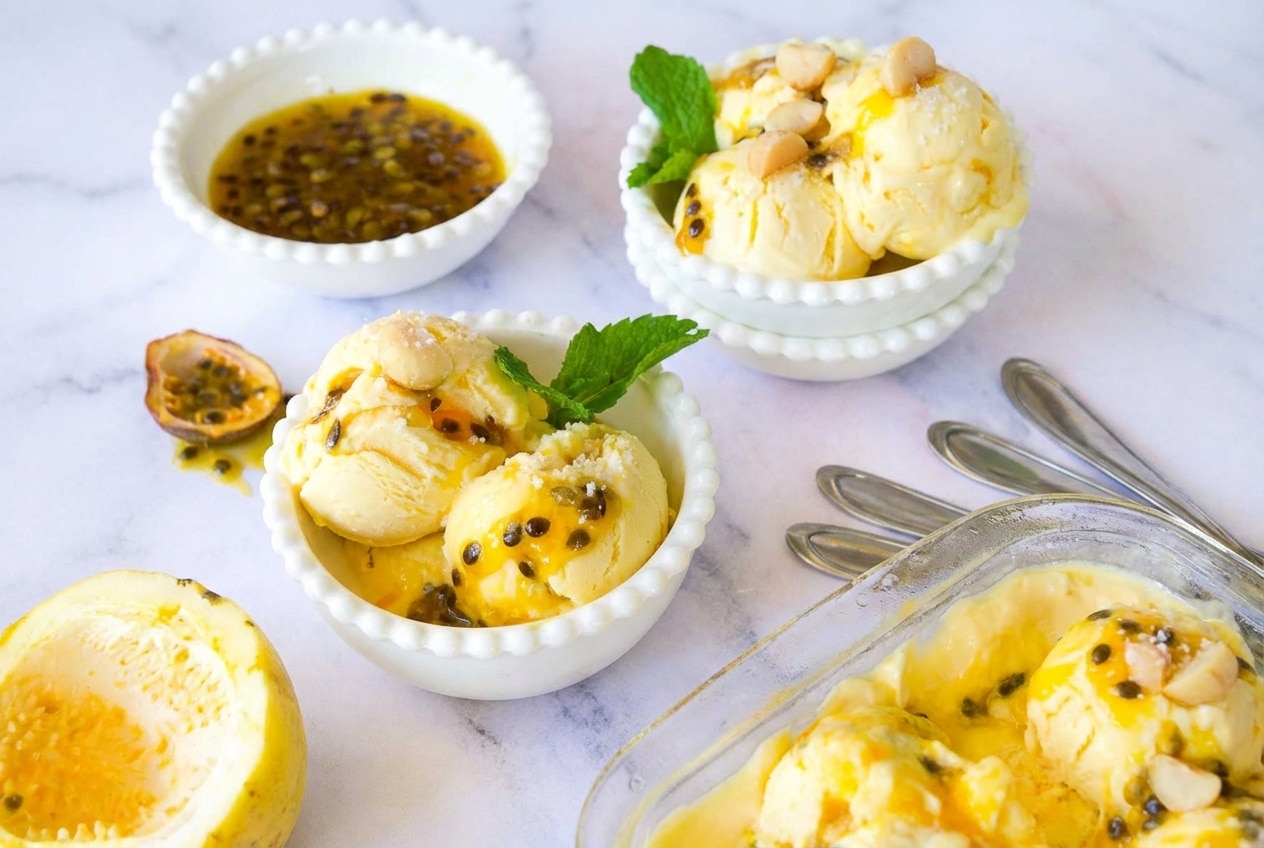 Scoops of Passion Fruit Ice Cream topped with toasted macadamia nuts, featuring a creamy, sea salt and rum-infused base.