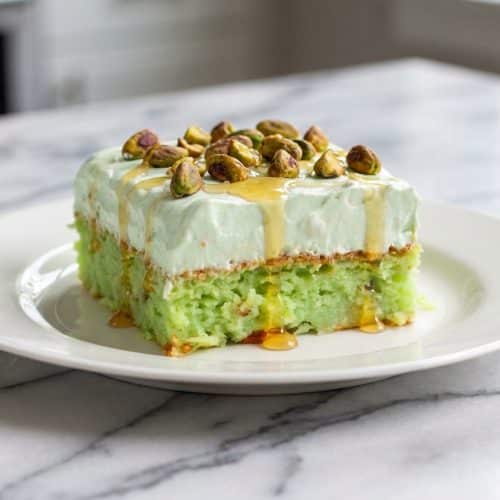 Pistachio Pineapple Paradise Cake topped with toasted pistachios, salted honey, and creamy coconut milk frosting.