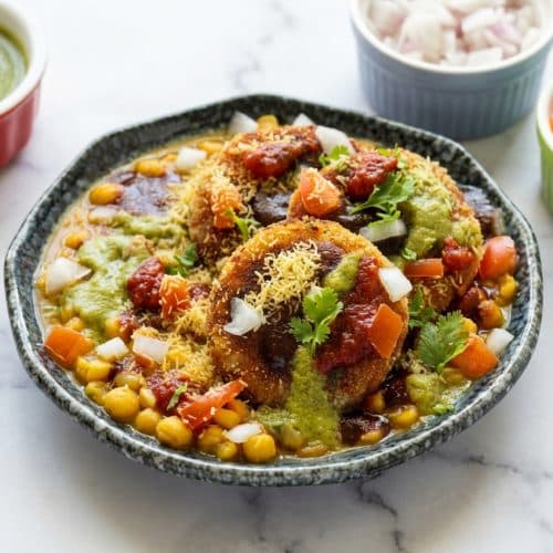 Golden brown ragda patties recipe featuring a double-crunch amchur crust topped with spicy white pea gravy and sev.