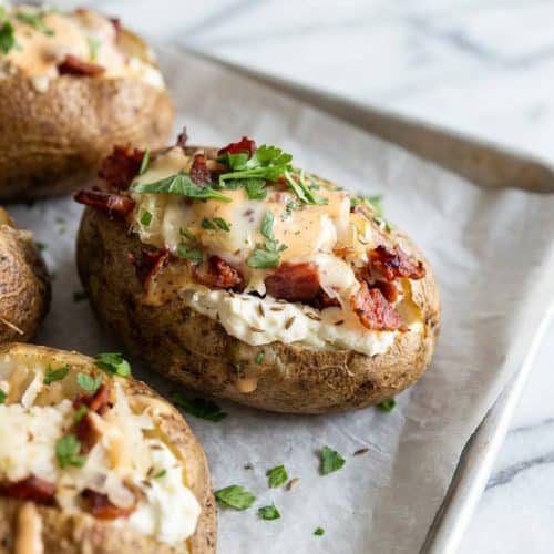 Reuben Stuffed Baked Potatoes topped with corned beef, dry pressed sauerkraut, and melted Swiss over a creamy caraway filling.