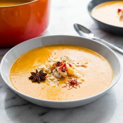 Creamy lobster bisque recipe bowl garnished with fresh herbs, infused with aromatic saffron and star anise.