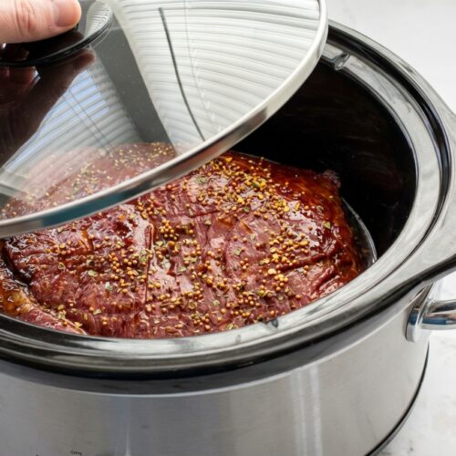 Slow cooker corned beef with a dark balsamic honey glaze and tender, pink center.