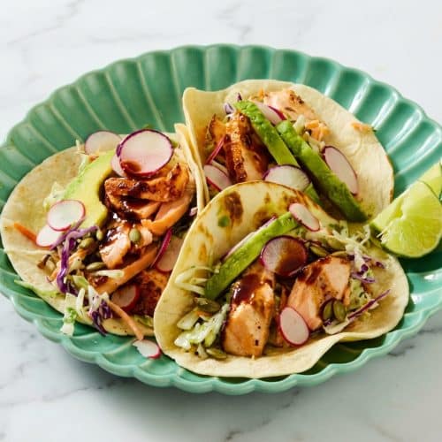 Salmon tacos topped with crunchy pepitas and a dark miso-chipotle glaze on warm tortillas.