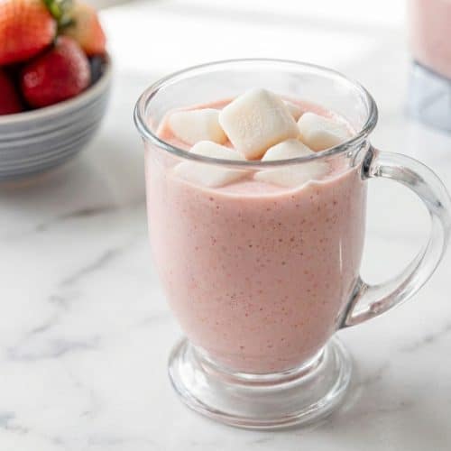A tall glass of creamy strawberry banana smoothie, made extra frosty and thick using the frosted milk cube technique.