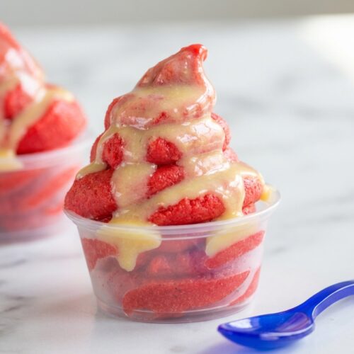 Swirled pink strawberry dole whip showing a silky coconut-pineapple emulsion texture in a glass bowl.
