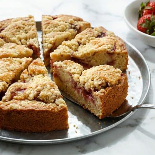 Slice of strawberry sour cream cake showing a deep red roasted strawberry and balsamic reduction swirl.