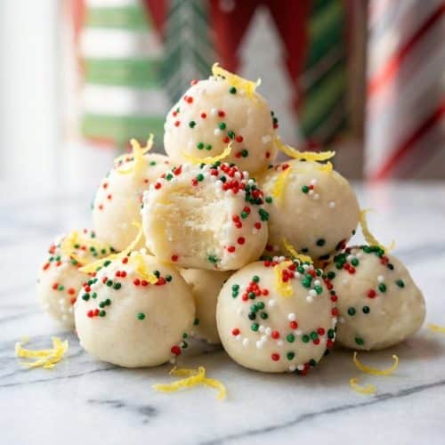 Golden white chocolate coated sugar cookie truffles topped with fresh lemon zest on a serving plate