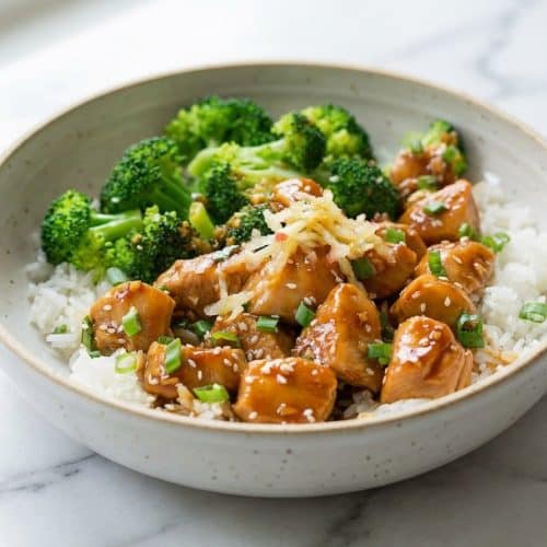 Glazed teriyaki chicken pieces softened with a grated Fuji apple tenderizer on a white plate.