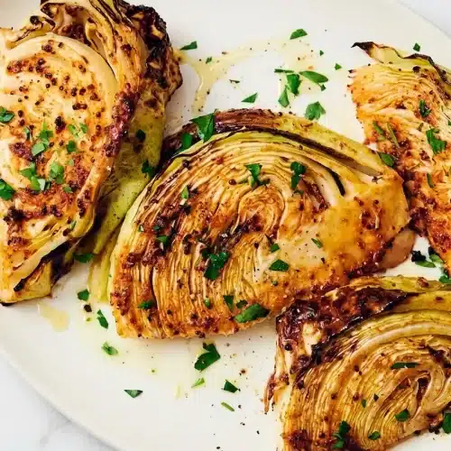 Air fryer cabbage wedges with crispy edges, coated in a maple-mustard glaze and dusted with freshly grated Parmesan cheese.
