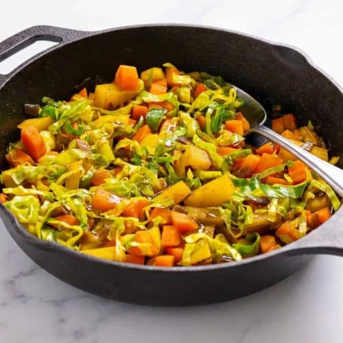 Ethiopian cabbage stew in a cast iron skillet using the faux niter kibbeh blooming technique for this atakilt wat recipe.