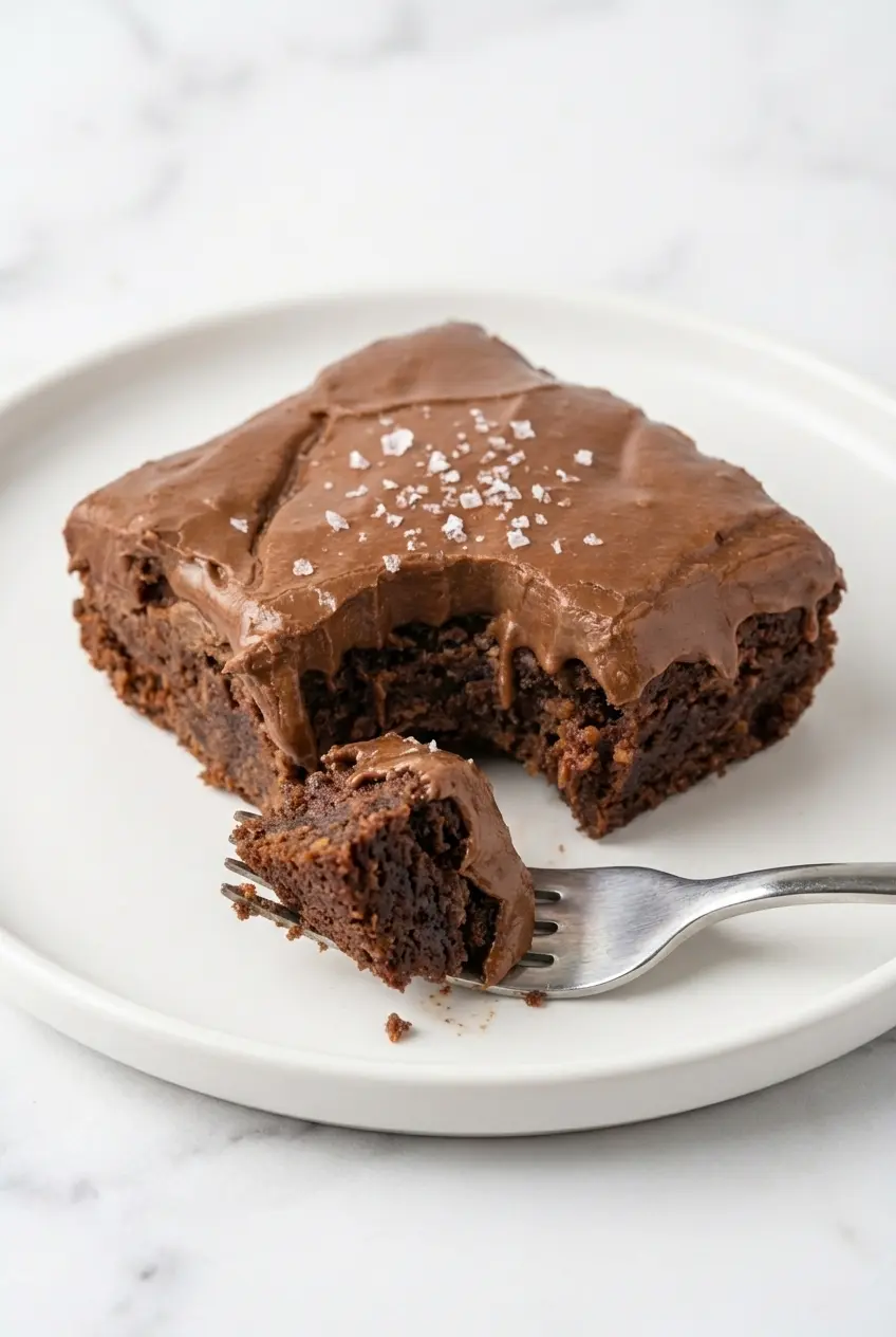 Freshly baked Lunch Lady Brownies in a 9x13 baking dish lined with parchment paper, ready for icing.