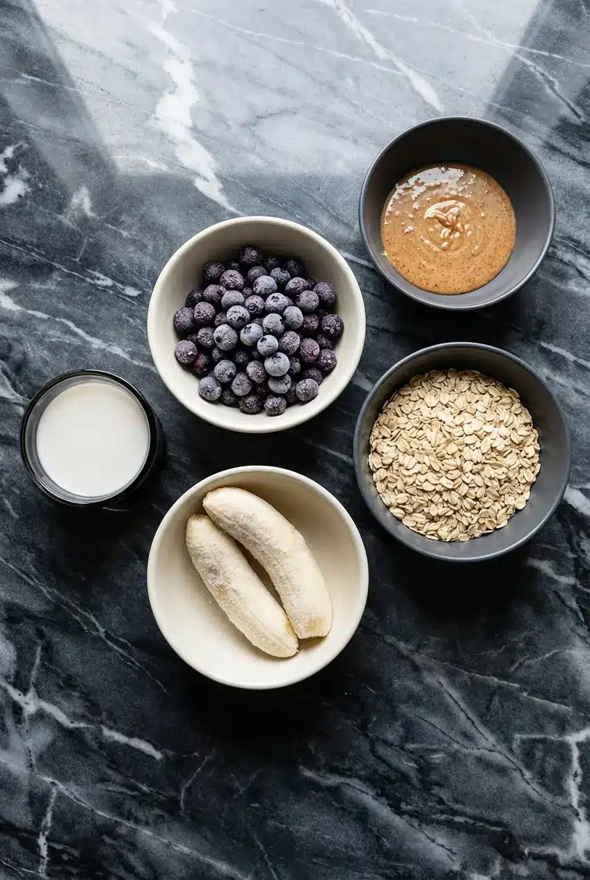 Raw ingredients for blueberry almond milk smoothie including berries, lemon, and seeds for omega-3 fatty acids.