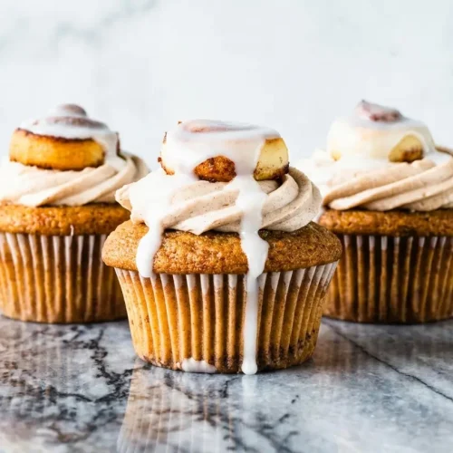 Cinnamon Roll Cupcakes topped with golden brown butter cream cheese frosting and a rich cinnamon swirl.