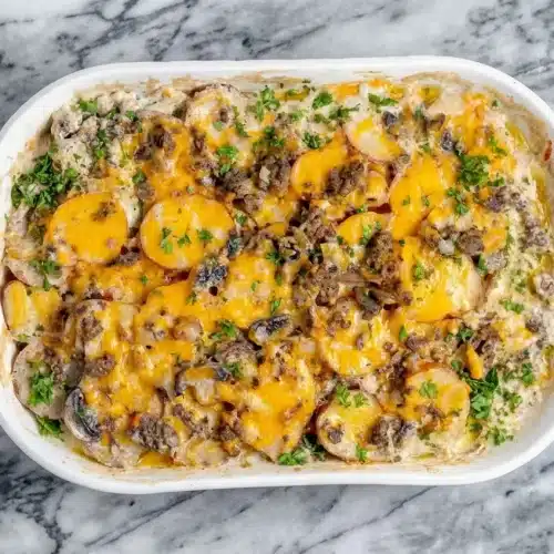 Golden cheesy hamburger potato casserole in a dish, with a savory sauce infused with tangy Dijon and Worcestershire.